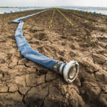 Very dry land - drought - and hose for watering
